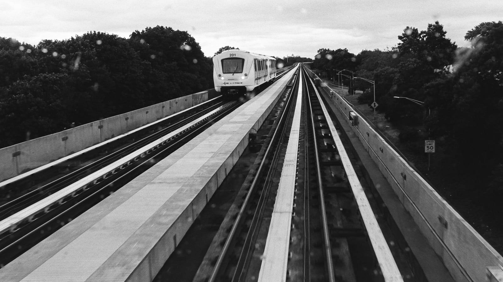 A JFK AirTrain car running on the elevated concrete guideway between stations