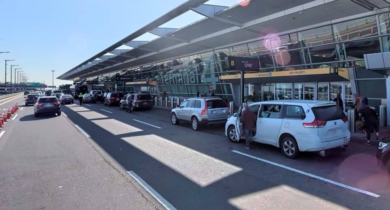 Cars dropping off at the JFK Terminal 4 departures curb, beside the Delta One and Sky Priority doors
