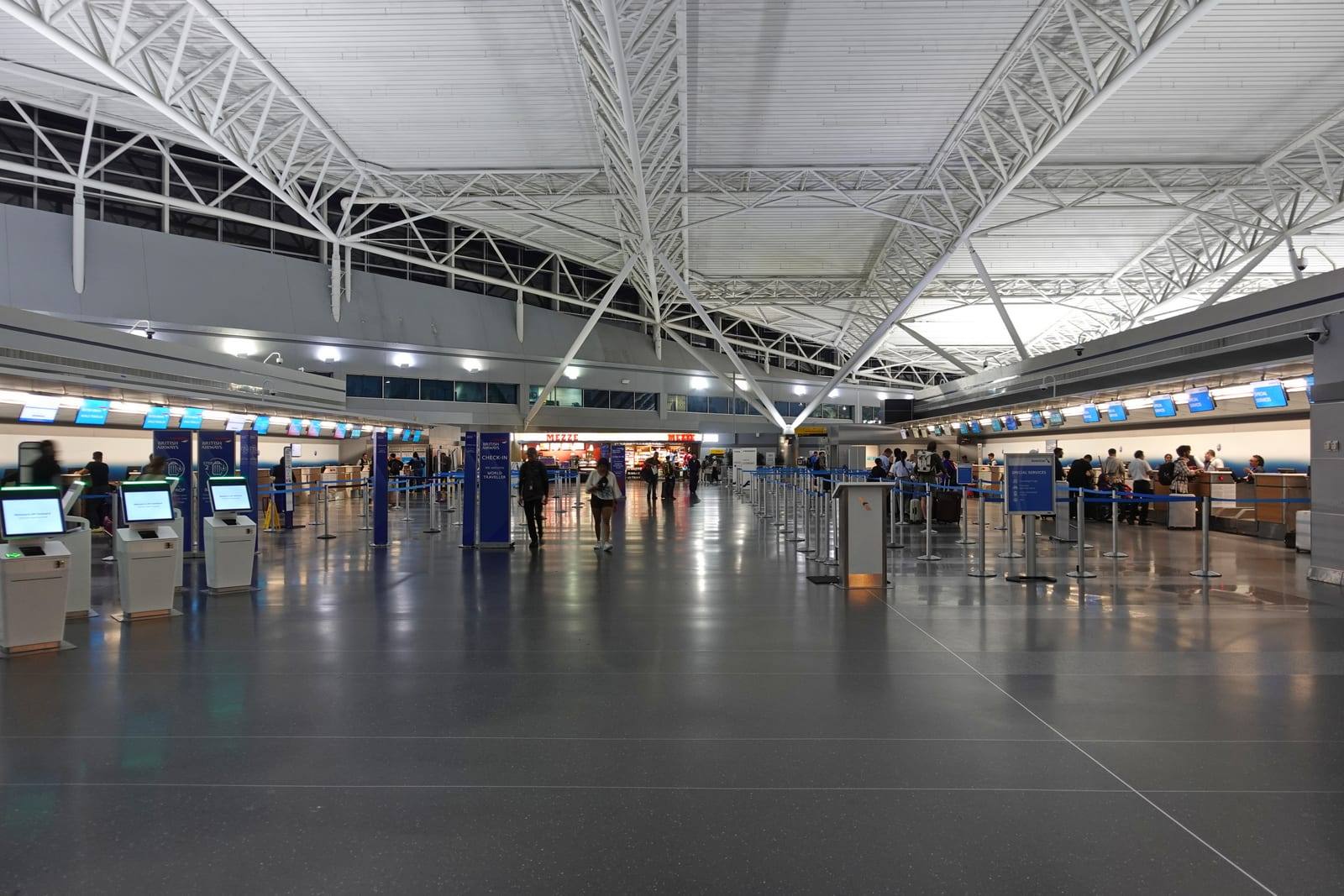 The JFK Terminal 8 check-in hall, with British Airways desks and self-service kiosks under the white roof trusses